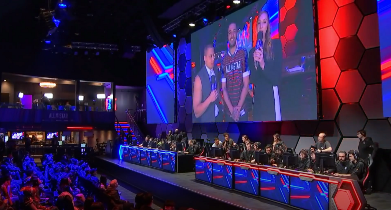 Esports players at desks on a lit stage
